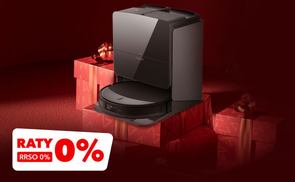 Na zdjęciu znajduje się ciemny odkurzacz automatyczny ustawiony na tle czerwonych pudełek prezentowych z kokardami. W lewym dolnym rogu widnieje biało-czerwony napis RATY 0%, RRSO 0%.
