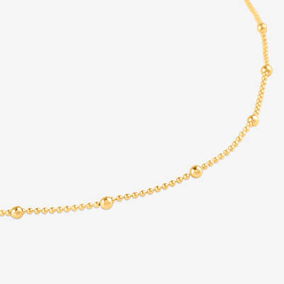 Close-up of delicate gold beaded station chain necklace on white background