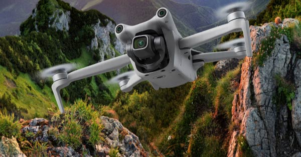 Dron unosi się nad malowniczym, górskim krajobrazem z bujną zielenią i skalistymi szczytami. W tle widać zalesione wzgórza i doliny, tworzące piękny, naturalny widok.