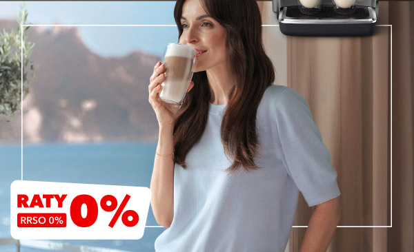 Na zdjęciu widoczna jest kobieta trzymająca szklankę z napojem, stojąca na tle zasłon i rozmytego krajobrazu z wodą i górami. W dolnym rogu znajduje się czerwony napis RATY 0%, RRSO 0%.
